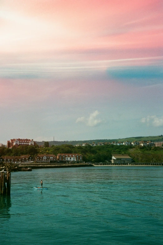 a man paddling a small boat towards a pier on a harbor