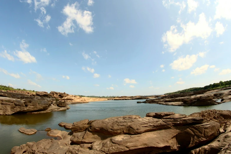 rocks in the water near a shore with blue skies