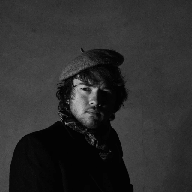 man in dark shirt and hat posing for camera