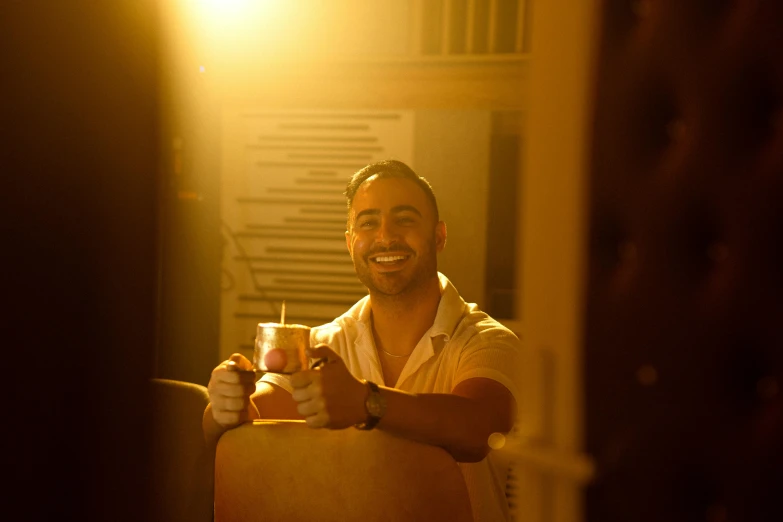 a man is holding a drink while sitting down