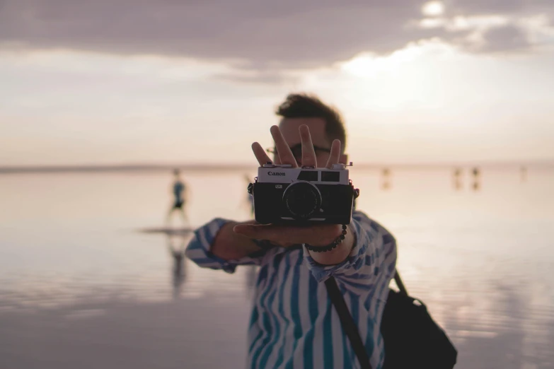 a person taking a picture with an old camera on a beach