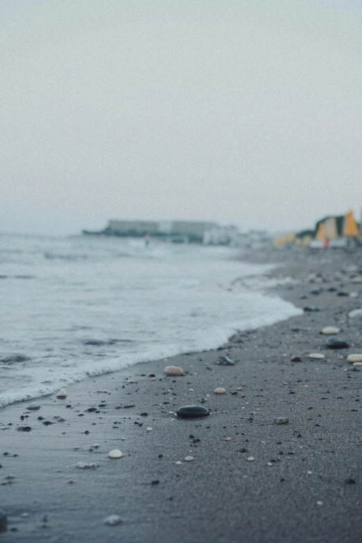 black beach and ocean with shells in water and buildings