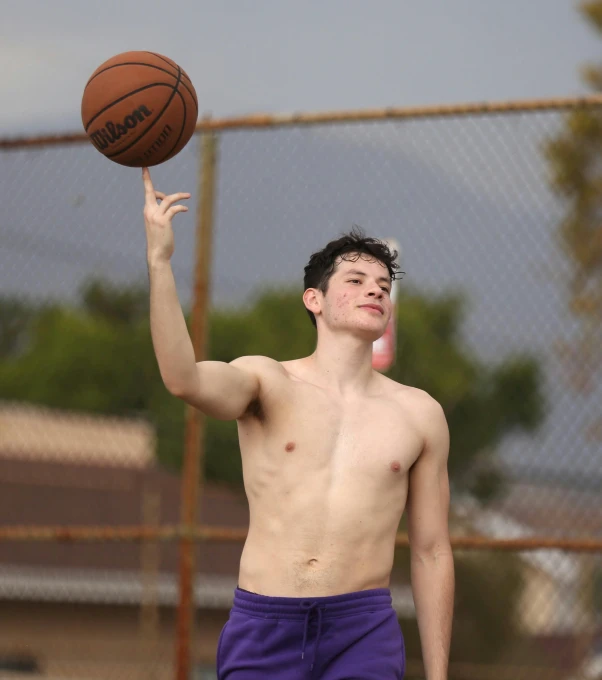 a shirtless young man holds a basketball