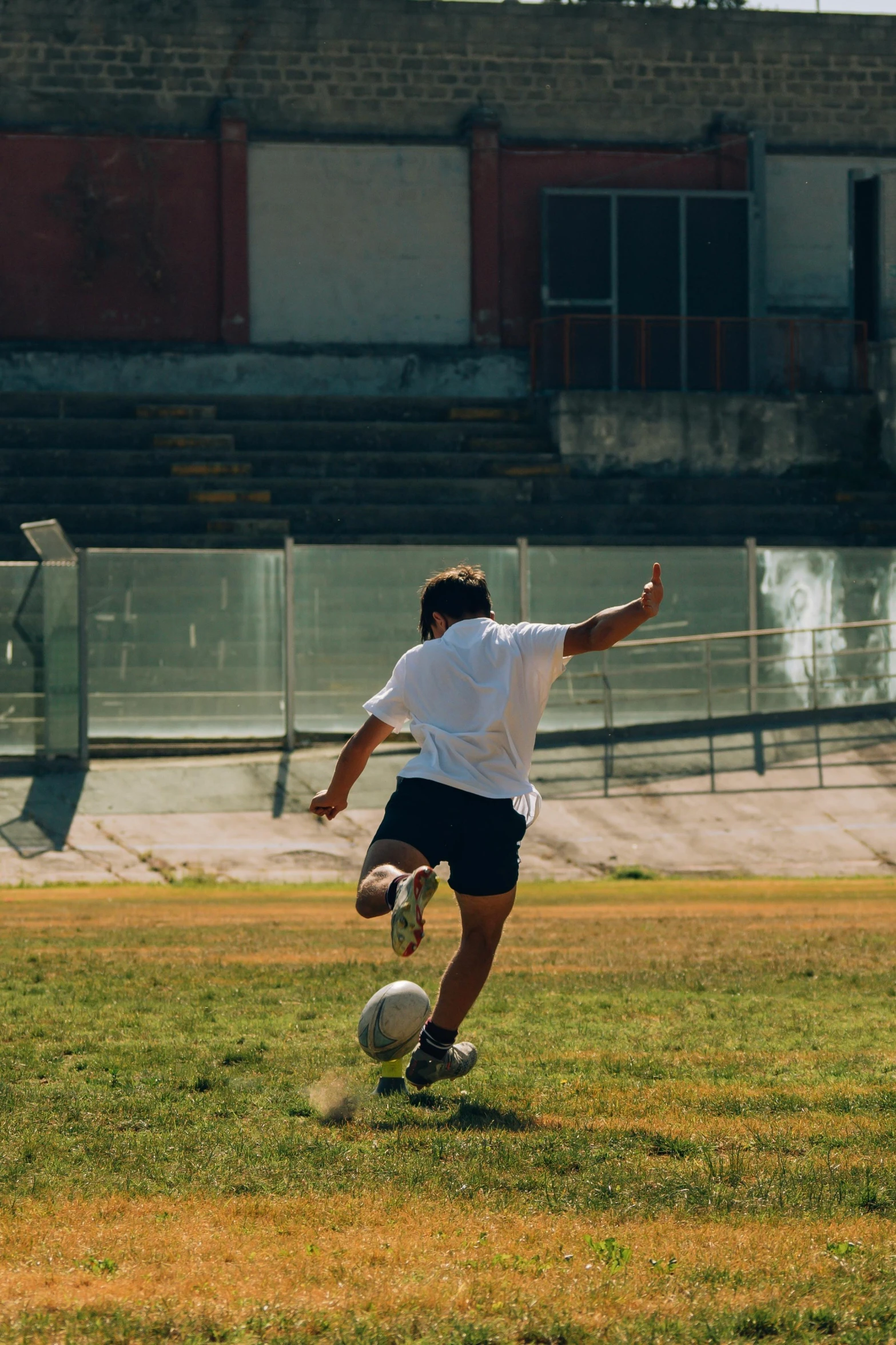 young man kicking soccer ball on open grassy field