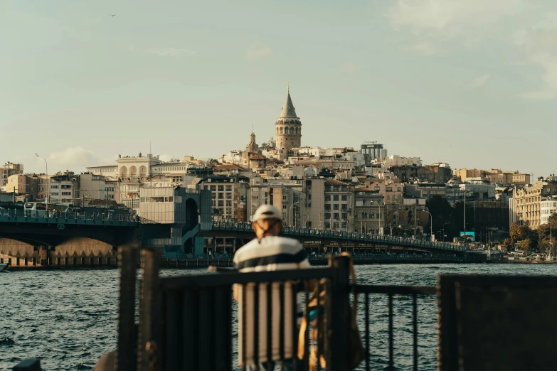 there is a man that is sitting on a pier overlooking the river