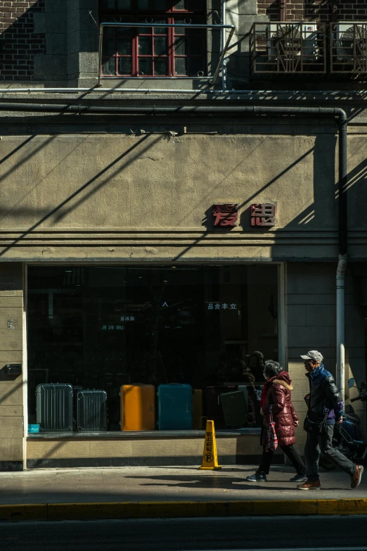 people walking by a commercial building in front of a gate