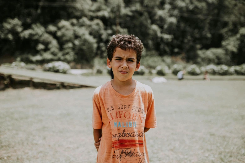 a small boy standing outside in the grass