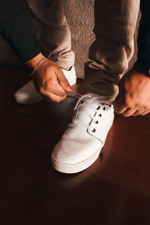 a person putting on white shoes on a table