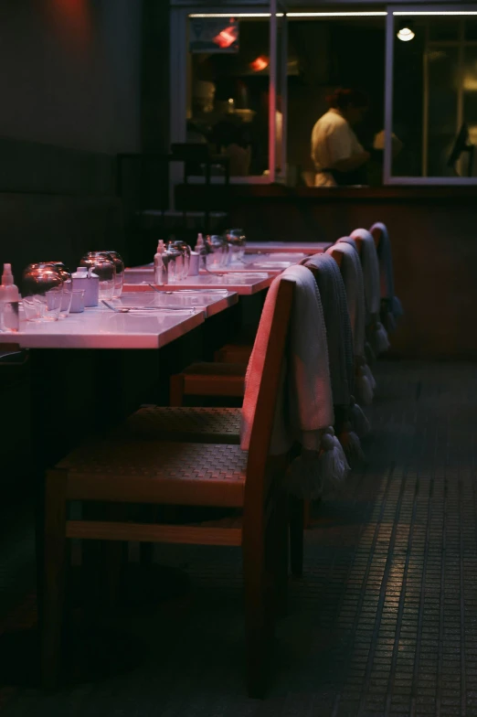 many bottles and glasses line the tables in a dimly lit restaurant