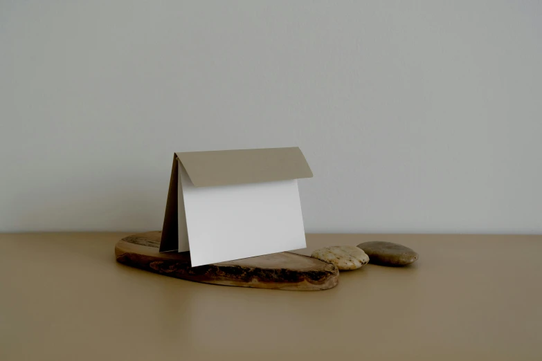 a paper house sitting on a piece of wood