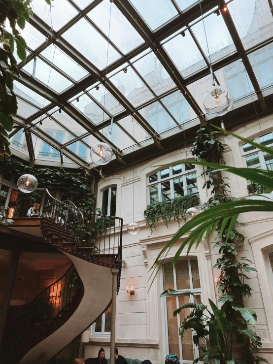 many people sitting on a table in a room with a glass roof