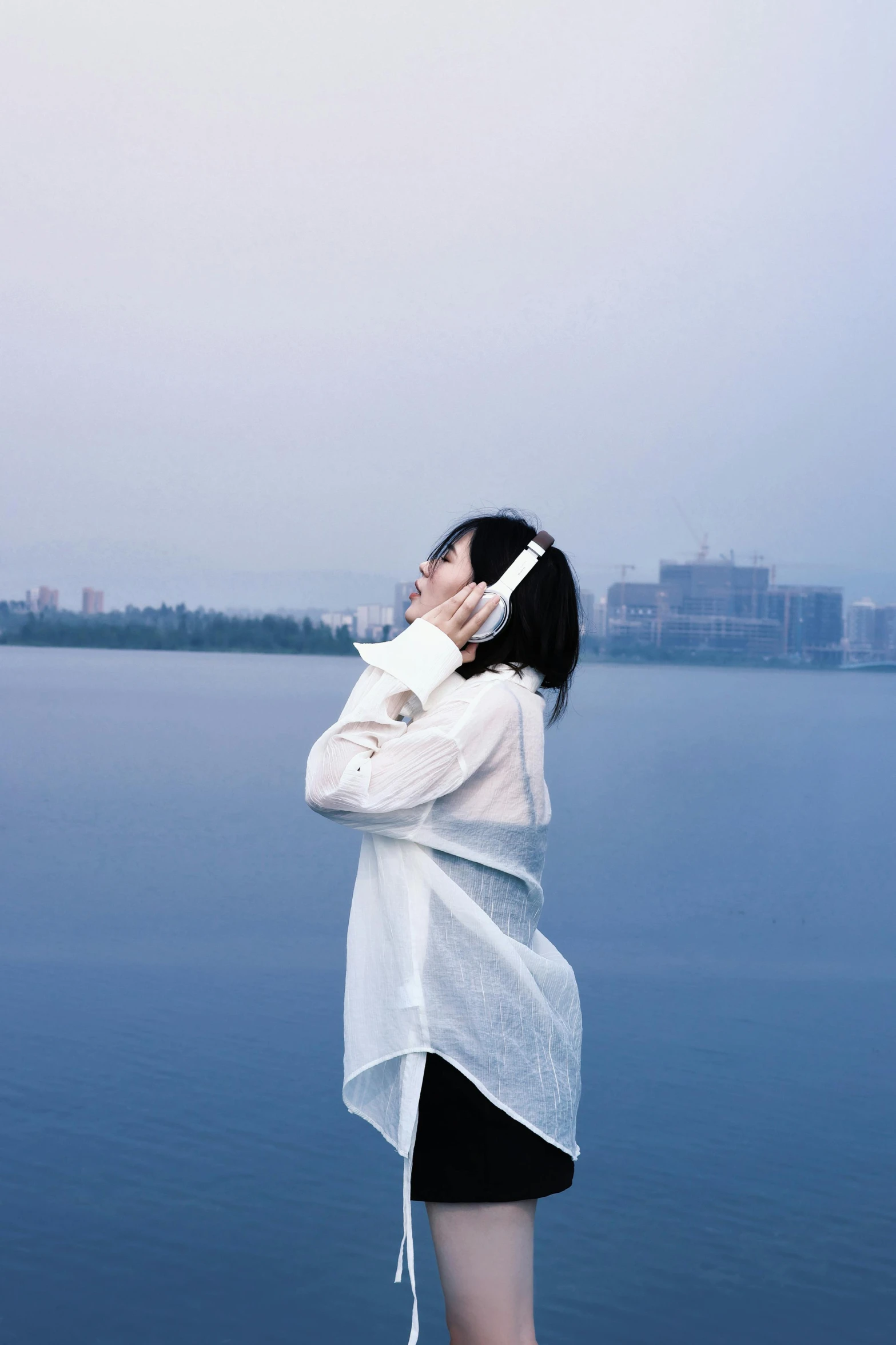 a person wearing a scarf over their neck standing in front of the ocean