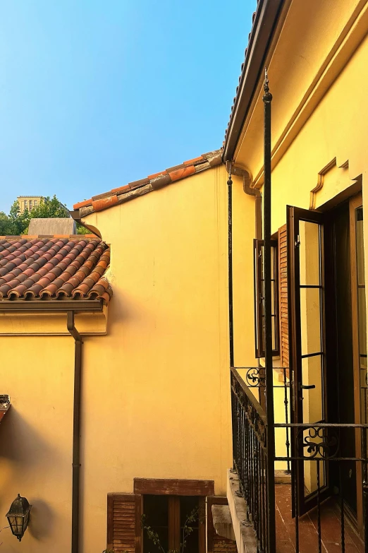 a patio area that has a yellow and brown wall and a black wrought iron rail