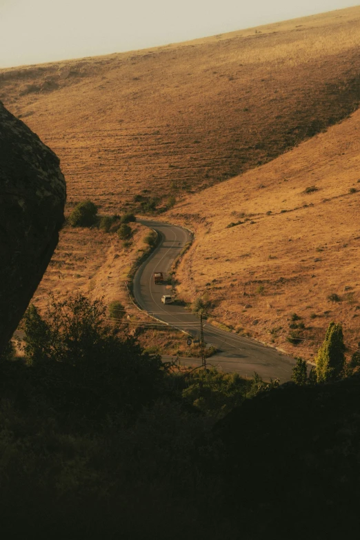 the road runs along an arid hillside on either side