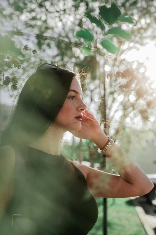 a lady standing in the sun looking at her hands on her face