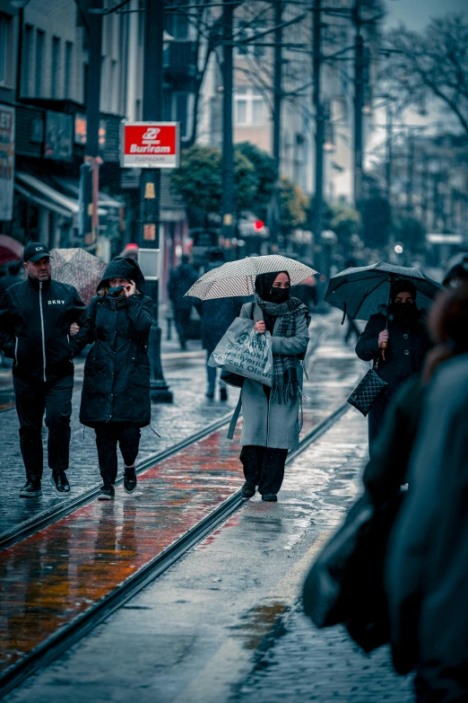 people holding umbrellas walk down a city street