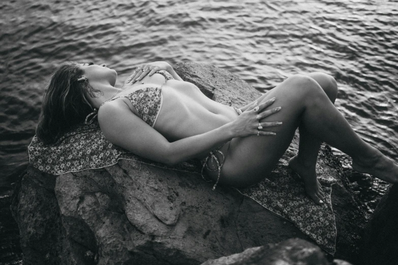 black and white pograph of a woman laying on rocks