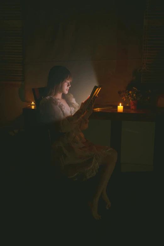 a woman sitting in a chair reading in the dark