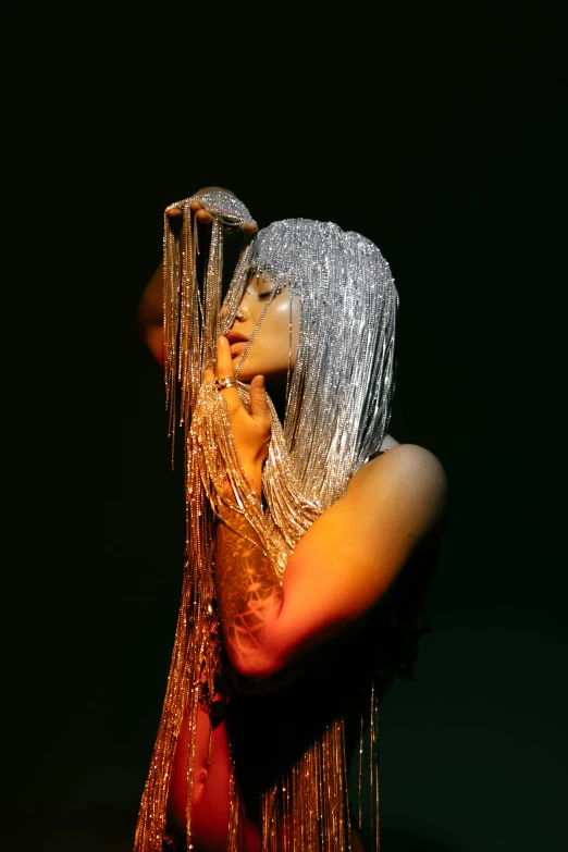 a person in a dark room holding their head covered with chains