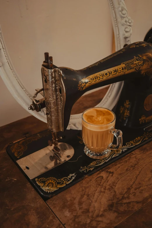 an old fashioned sewing machine with a cup of cappuccino