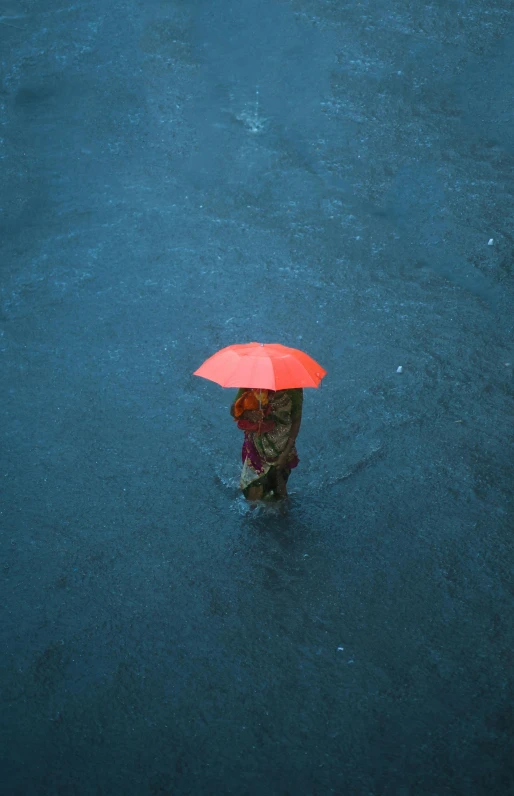 person walking on the floor in rain with an orange umbrella