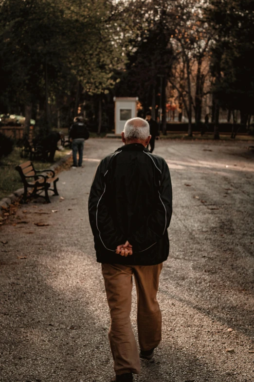 a man walking down a paved road next to trees