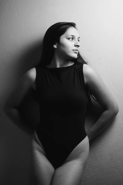 a woman in a bodysuit poses with her hands on her hips