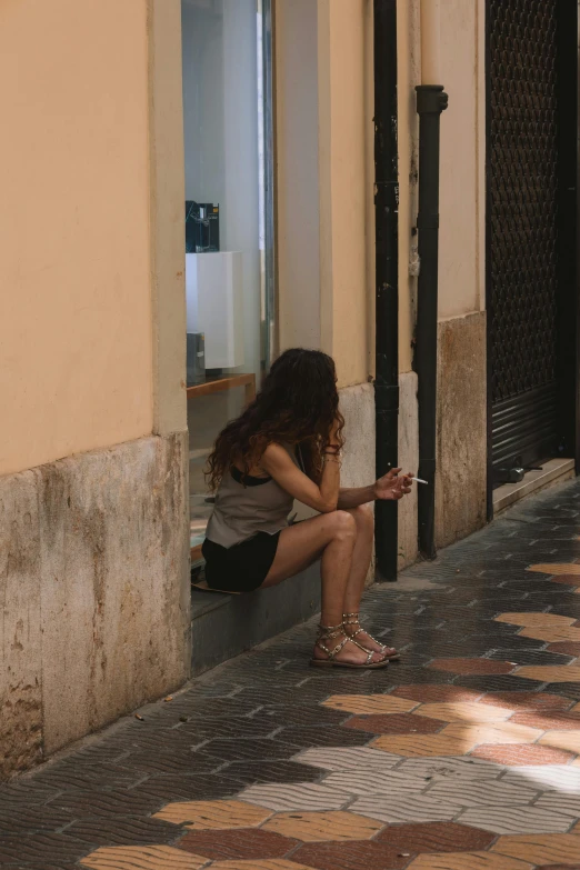 a girl sitting on a wall by herself looking at her cell phone