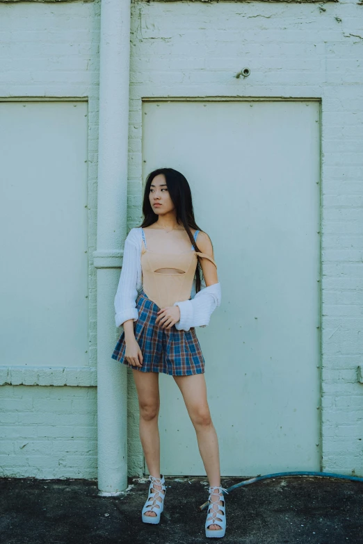 young woman with torn shirt and plaid skirt posing for a po