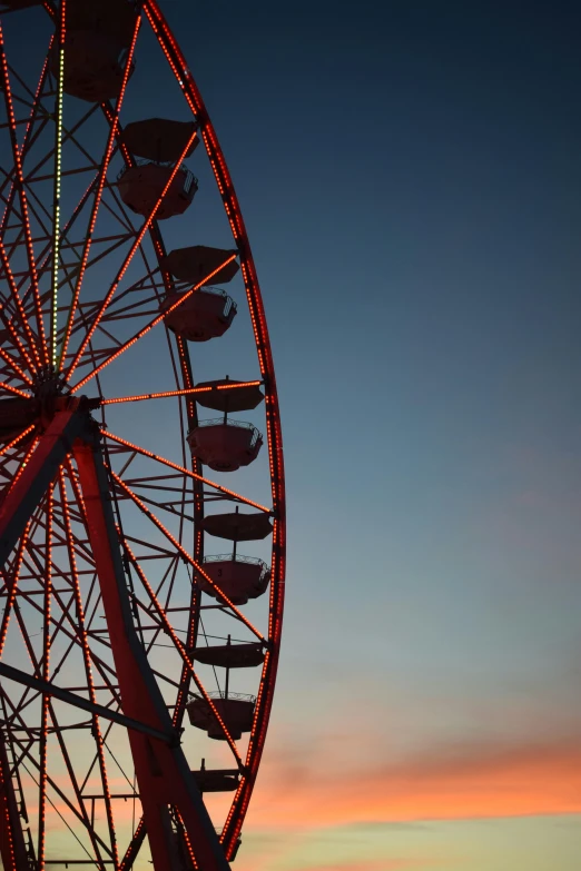 a red ferris wheel is shown against a sunset sky