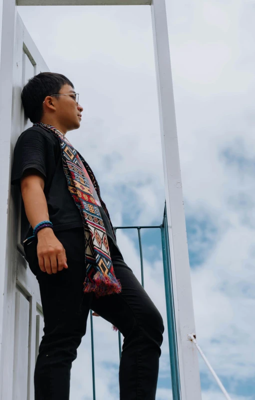 man in ethnic dress leaning on metal stairs