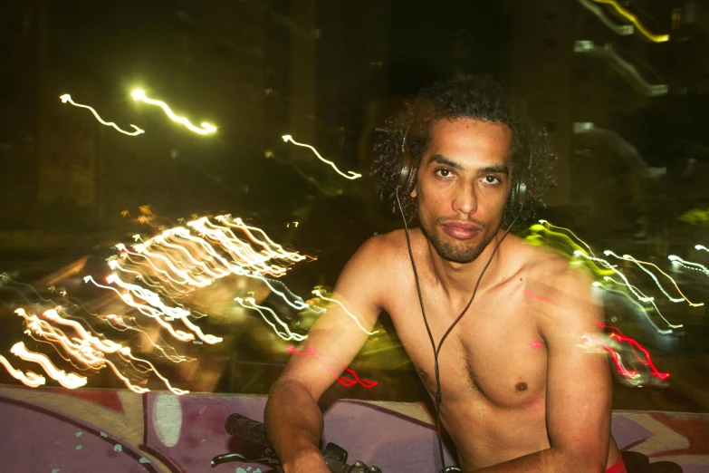 shirtless man looking at camera with headphones on at night