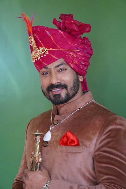 an indian male holding an umbrella in front of a green background