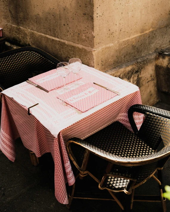 a table sits between two chairs outside on the sidewalk