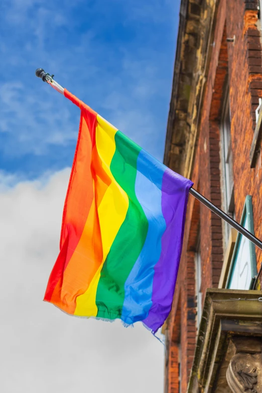 the rainbow flag on a balcony next to a brick building