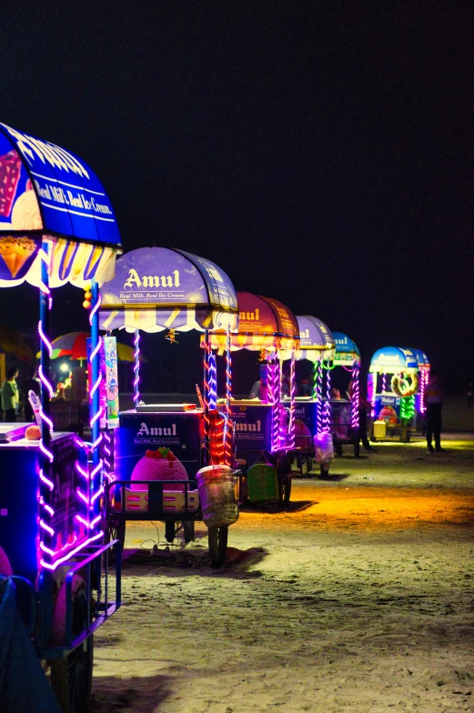 an array of food carts are in line under the dark sky