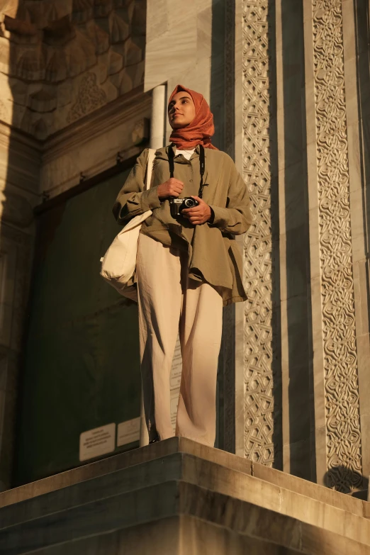 woman wearing beige outfit standing in front of an ornate building