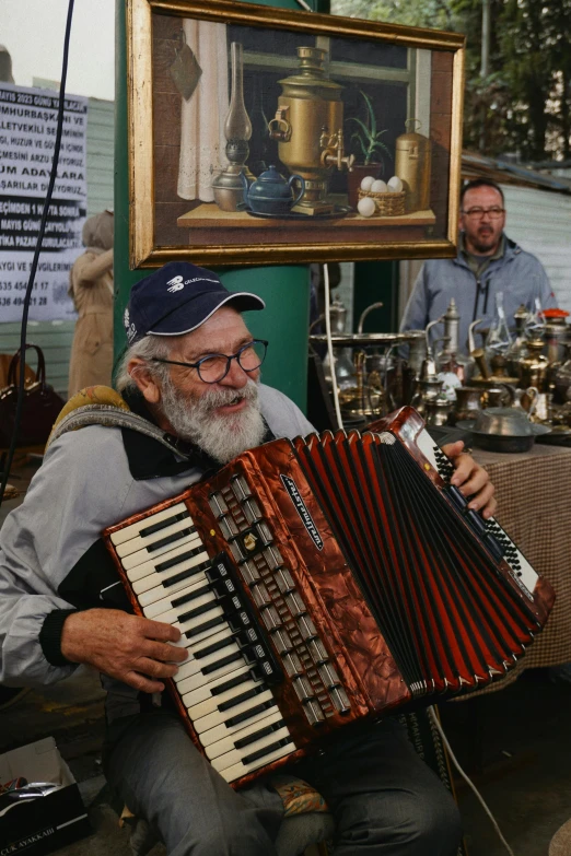 a man is sitting and holding an antique red accordian