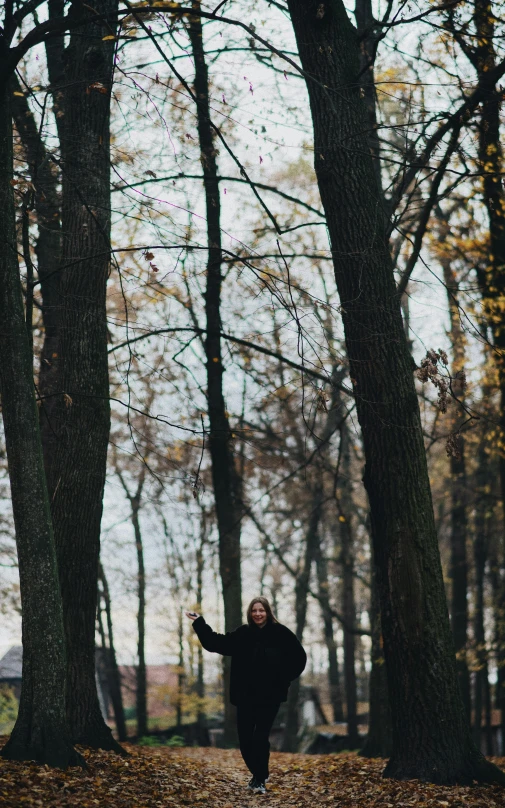 a woman in black is running through the woods