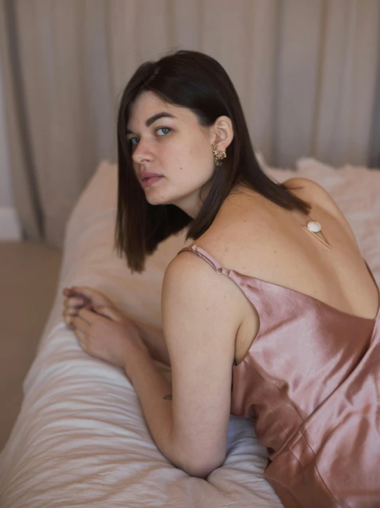 woman wearing off the shoulder dress and gold earring laying on bed