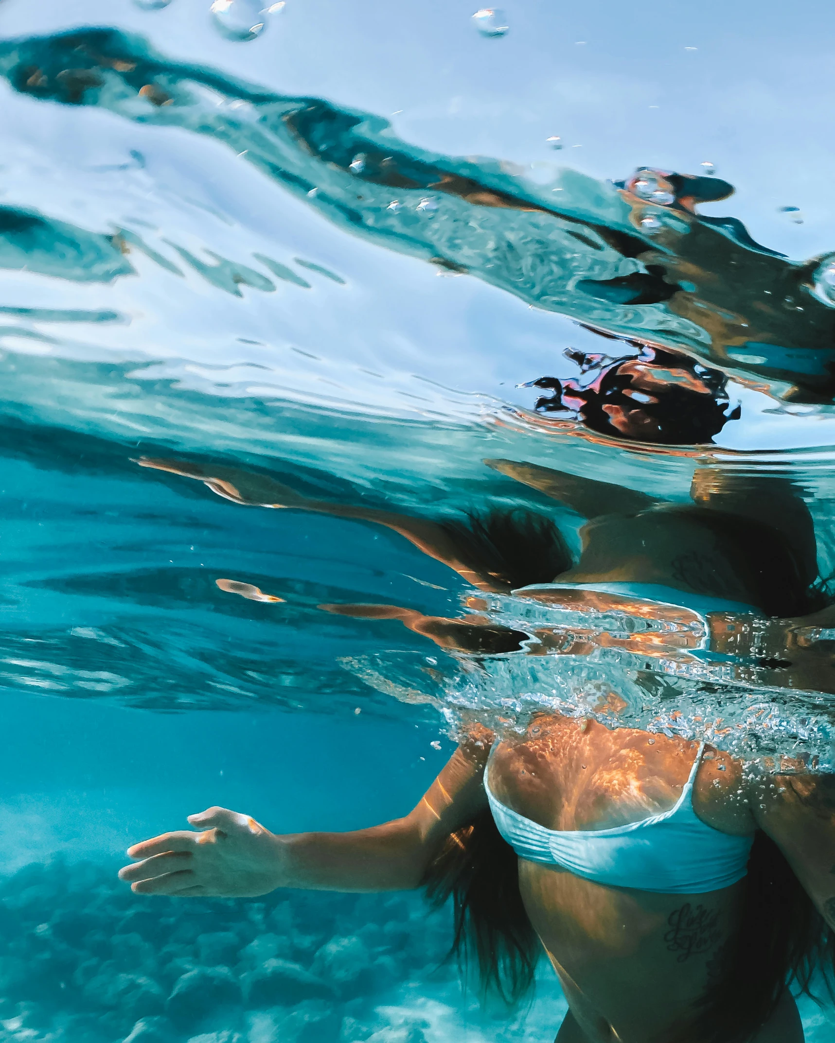 woman swims through blue waters on clear day