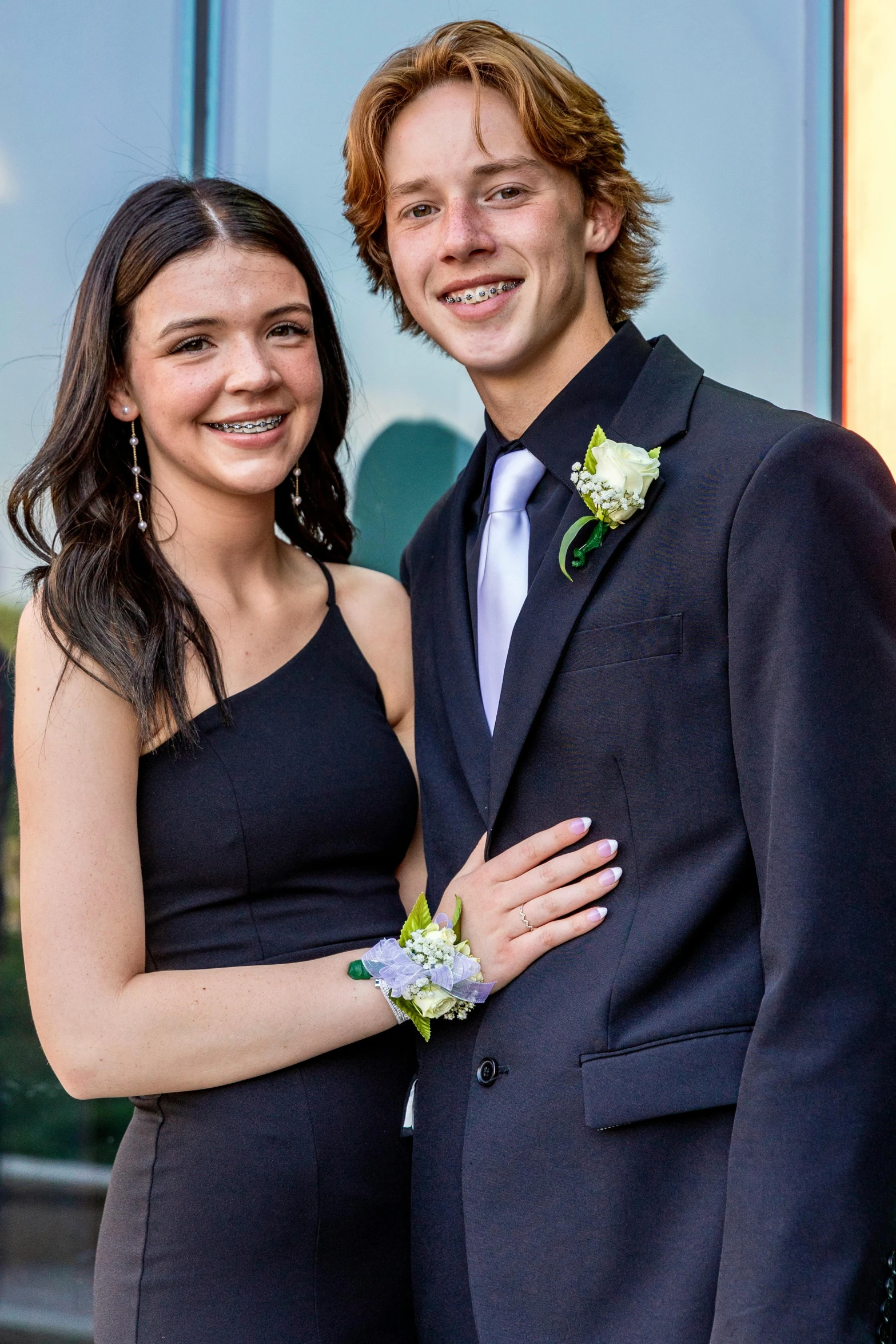 a girl standing next to a man in a suit and tie