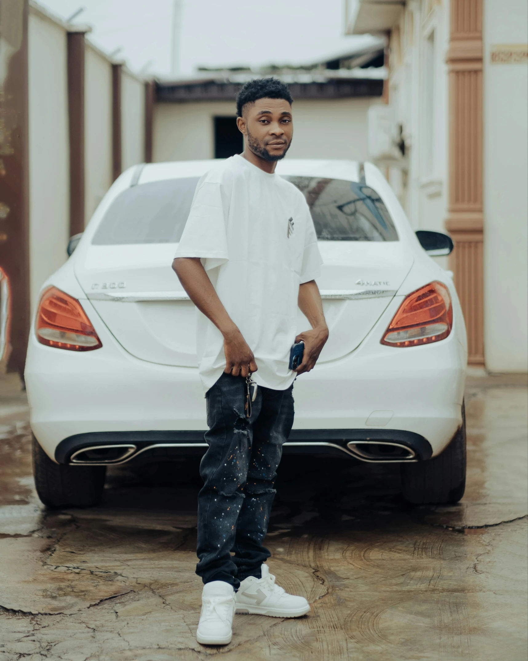 a young man standing in front of a white car