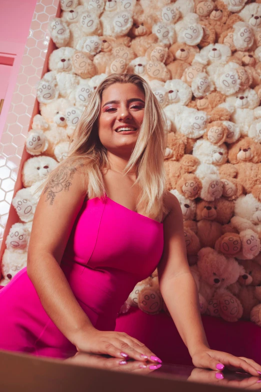 a woman in pink poses with a bunch of teddy bears