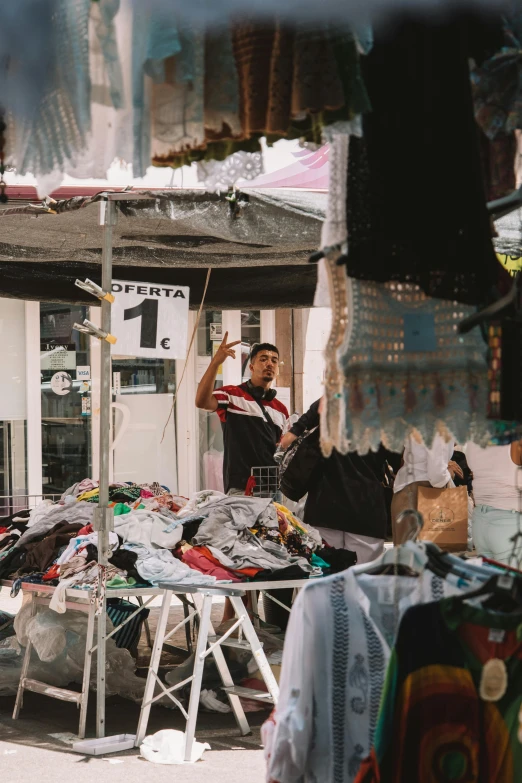 man waving on the street in front of his clothing store