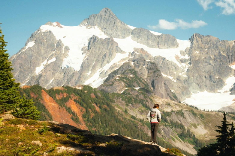 a person stands on top of a mountain looking at the view