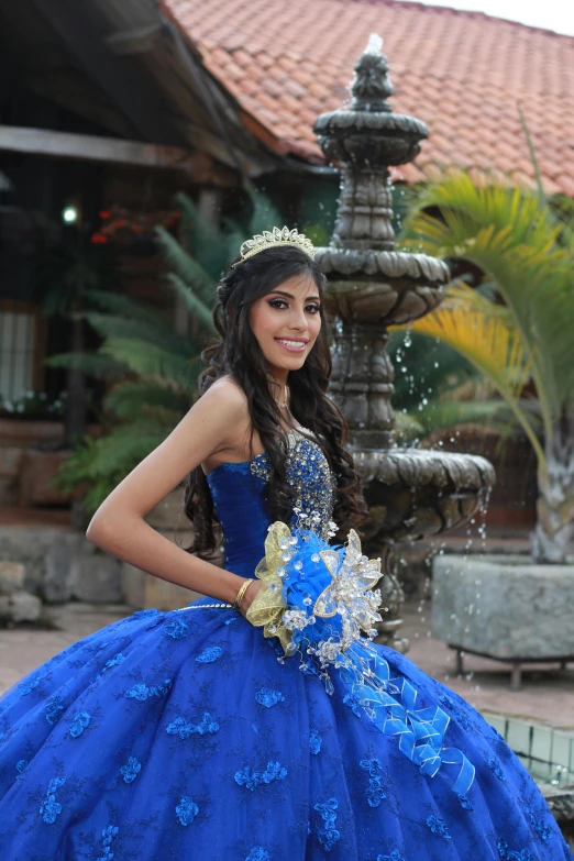 a girl in a blue dress stands next to a fountain