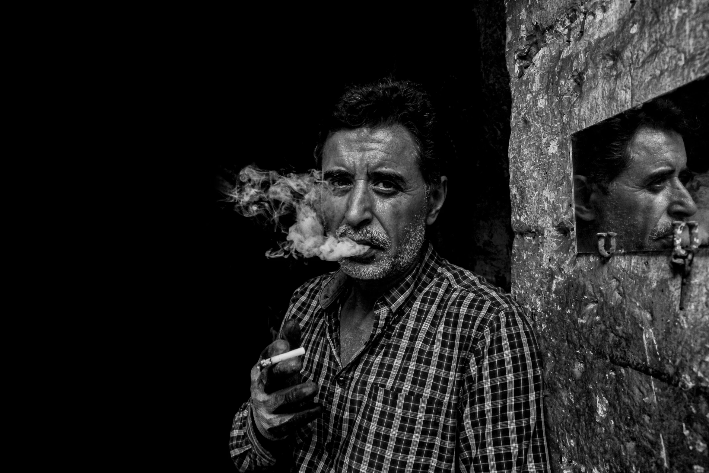 a man smoking cigarettes by a doorway, with a woman looking at him