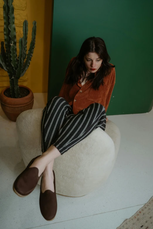 the girl is sitting on a big rock in a room with cactus