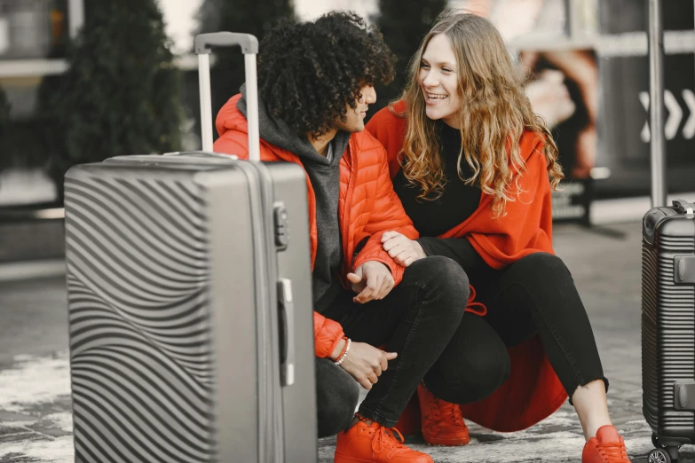 two women hugging their luggage on the side of the street